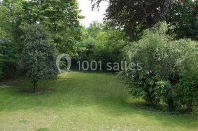 Grande maison en briques rouges avec deux tours, entourée de pelouse et de voitures garées devant.