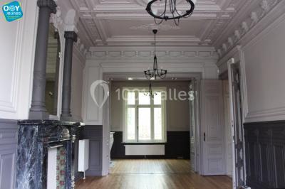 Grande maison en briques rouges avec deux tours, entourée de pelouse et de voitures garées devant.