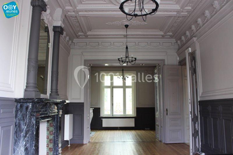 Intérieur d'une pièce lumineuse avec moulures au plafond, cheminée en marbre et parquet en bois clair.