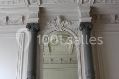 Grande maison en briques rouges avec deux tours, entourée de pelouse et de voitures garées devant.