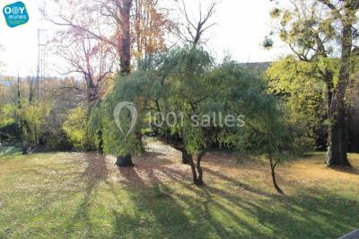 Grande maison en briques rouges avec deux tours, entourée de pelouse et de voitures garées devant.