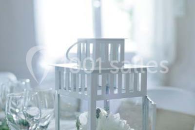 Une mariée en robe blanche est assise sur un banc en bois décoré des lettres ’A&J’, tenant un bouquet de fleurs.