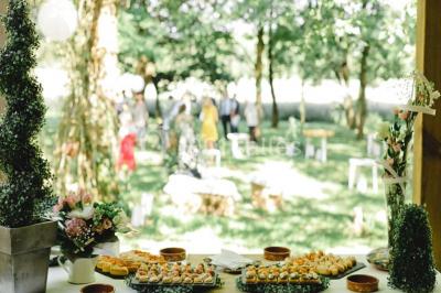 Une mariée en robe blanche est assise sur un banc en bois décoré des lettres ’A&J’, tenant un bouquet de fleurs.