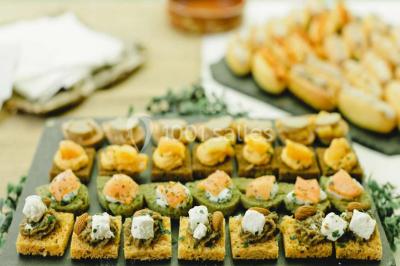 Une mariée en robe blanche est assise sur un banc en bois décoré des lettres ’A&J’, tenant un bouquet de fleurs.