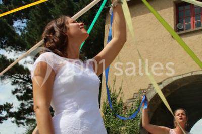 Une mariée en robe blanche est assise sur un banc en bois décoré des lettres ’A&J’, tenant un bouquet de fleurs.