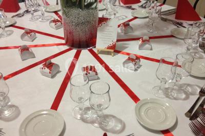 Une mariée en robe blanche est assise sur un banc en bois décoré des lettres ’A&J’, tenant un bouquet de fleurs.