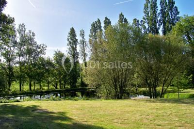 Une mariée en robe blanche est assise sur un banc en bois décoré des lettres ’A&J’, tenant un bouquet de fleurs.