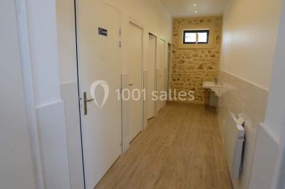 Vue aérienne d'un jardin arboré avec des allées herbeuses, entouré de champs et de quelques bâtiments résidentiels.