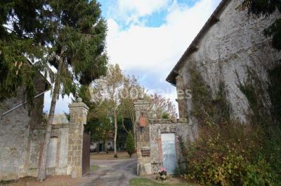 Vue aérienne d'un jardin arboré avec des allées herbeuses, entouré de champs et de quelques bâtiments résidentiels.