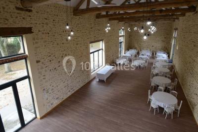 Vue aérienne d'un jardin arboré avec des allées herbeuses, entouré de champs et de quelques bâtiments résidentiels.