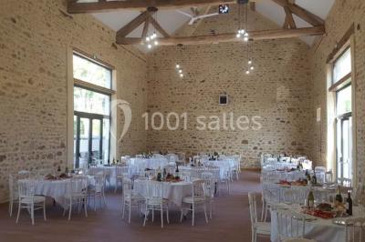 Vue aérienne d'un jardin arboré avec des allées herbeuses, entouré de champs et de quelques bâtiments résidentiels.