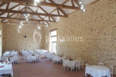 Vue aérienne d'un jardin arboré avec des allées herbeuses, entouré de champs et de quelques bâtiments résidentiels.