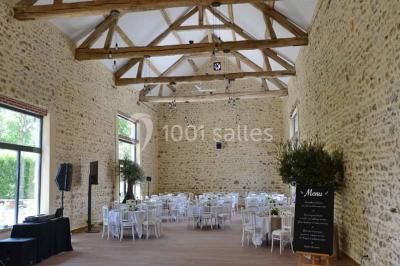 Vue aérienne d'un jardin arboré avec des allées herbeuses, entouré de champs et de quelques bâtiments résidentiels.