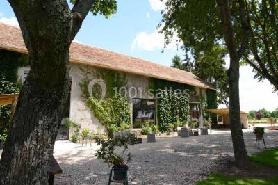 Vue aérienne d'un jardin arboré avec des allées herbeuses, entouré de champs et de quelques bâtiments résidentiels.