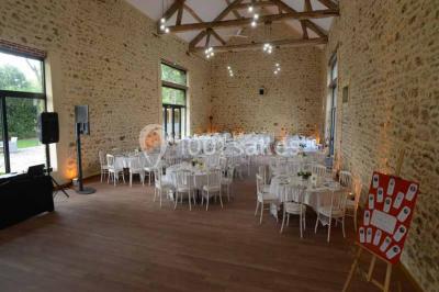 Vue aérienne d'un jardin arboré avec des allées herbeuses, entouré de champs et de quelques bâtiments résidentiels.