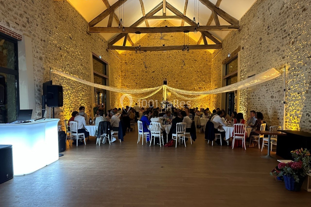 Salle de réception en pierre avec des invités assis à des tables, éclairage chaleureux et décoration lumineuse suspendue.