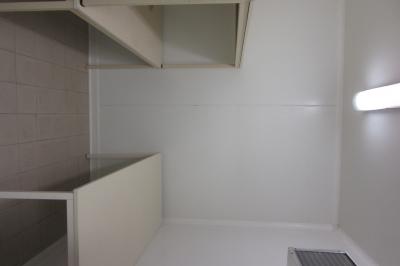 Salle lumineuse avec grandes fenêtres, mobilier en rotin gris et poutres apparentes, donnant sur un espace extérieur…