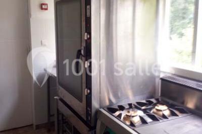 Évier double en inox avec robinet flexible, lave-vaisselle professionnel et sol en carrelage beige dans une cuisine.