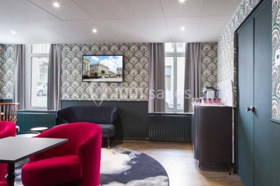 Une femme présente des informations sur un écran à trois personnes assises dans une salle de réunion décorée.