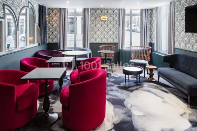 Une femme présente des informations sur un écran à trois personnes assises dans une salle de réunion décorée.