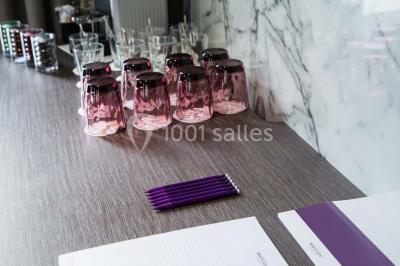 Une femme présente des informations sur un écran à trois personnes assises dans une salle de réunion décorée.