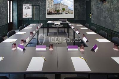 Une femme présente des informations sur un écran à trois personnes assises dans une salle de réunion décorée.