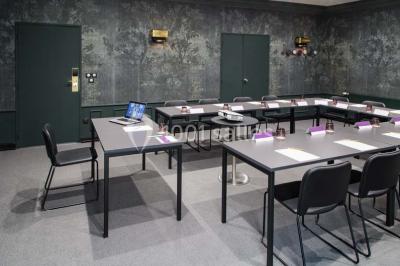 Une femme présente des informations sur un écran à trois personnes assises dans une salle de réunion décorée.