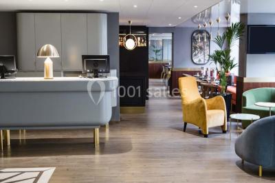 Une femme présente des informations sur un écran à trois personnes assises dans une salle de réunion décorée.