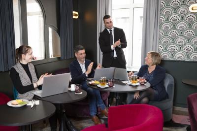 Une femme présente des informations sur un écran à trois personnes assises dans une salle de réunion décorée.