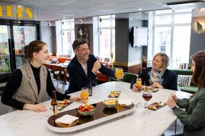 Une femme présente des informations sur un écran à trois personnes assises dans une salle de réunion décorée.