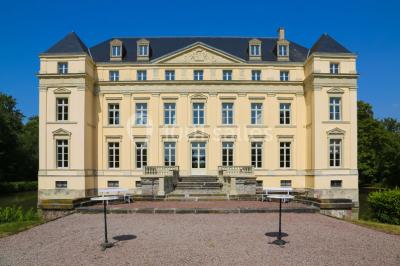 Salon lumineux avec parquet, mobilier classique, table ronde dressée au centre et lustre en cristal au plafond.
