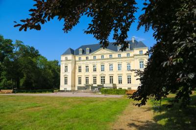 Salon lumineux avec parquet, mobilier classique, table ronde dressée au centre et lustre en cristal au plafond.
