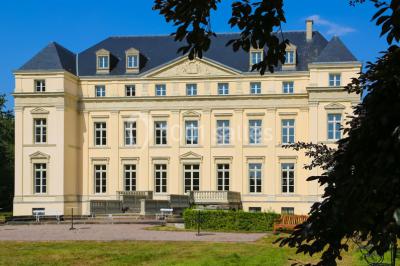 Salon lumineux avec parquet, mobilier classique, table ronde dressée au centre et lustre en cristal au plafond.