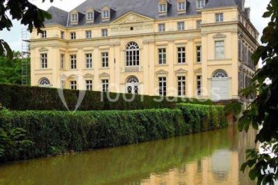 Salon lumineux avec parquet, mobilier classique, table ronde dressée au centre et lustre en cristal au plafond.