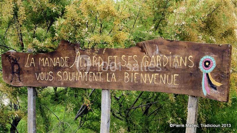 Panneau en bois gravé accueillant les visiteurs à la manade Allard, entouré de végétation.