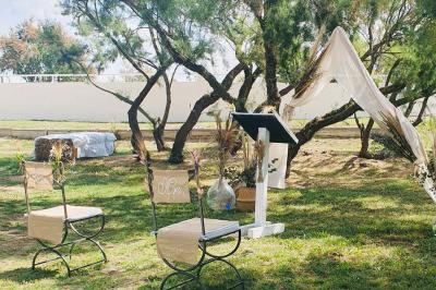 Chemin en gravier bordé de barrières en bois, entouré d'arbres et d'herbe sous un ciel dégagé.