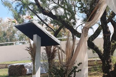 Chemin en gravier bordé de barrières en bois, entouré d'arbres et d'herbe sous un ciel dégagé.
