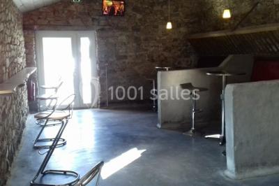 Chemin gravillonné bordé de barrières en bois menant à un bâtiment en pierre entouré de verdure.