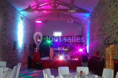 Chemin gravillonné bordé de barrières en bois menant à un bâtiment en pierre entouré de verdure.