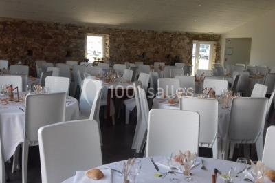 Chemin gravillonné bordé de barrières en bois menant à un bâtiment en pierre entouré de verdure.