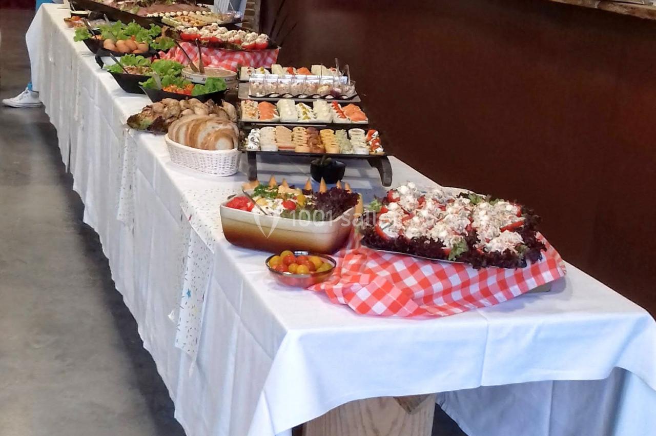 Buffet varié disposé sur une longue table avec plats sucrés et salés dans une salle aux murs en pierre.