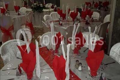 Salon de jardin en rotin avec coussins clairs, table basse décorée de fleurs, sur un sol pavé en extérieur.