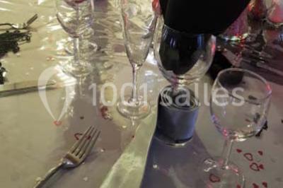 Salon de jardin en rotin avec coussins clairs, table basse décorée de fleurs, sur un sol pavé en extérieur.