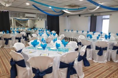 Salon de jardin en rotin avec coussins clairs, table basse décorée de fleurs, sur un sol pavé en extérieur.