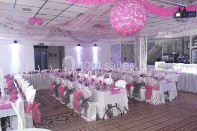 Salon de jardin en rotin avec coussins clairs, table basse décorée de fleurs, sur un sol pavé en extérieur.