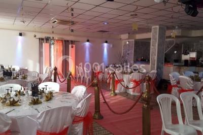 Salon de jardin en rotin avec coussins clairs, table basse décorée de fleurs, sur un sol pavé en extérieur.