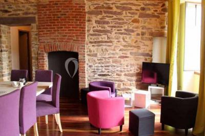 Cabane en bois perchée dans les arbres, entourée de forêt et bordée d'une prairie verdoyante.