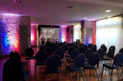 Cabane en bois perchée dans les arbres, entourée de forêt et bordée d'une prairie verdoyante.