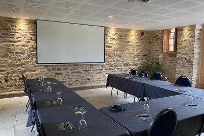 Cabane en bois perchée dans les arbres, entourée de forêt et bordée d'une prairie verdoyante.