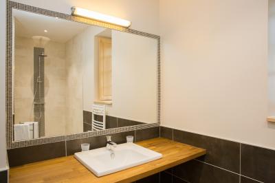 Cabane en bois perchée dans les arbres, entourée de forêt et bordée d'une prairie verdoyante.